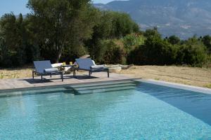 two chairs and a table next to a swimming pool at Villa Anemeli in Spartia +34 photos