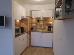 a small kitchen with white cabinets and a microwave at Ferienwohnung M Löffler in Lörrach