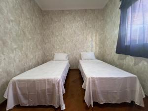two beds in a room with white sheets at Angel Hospedagem Itapuã in Vila Velha