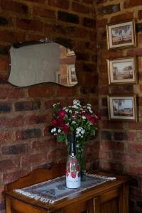 een vaas met bloemen op een tafel met een stenen muur bij Stone Cottage in Tierpoort