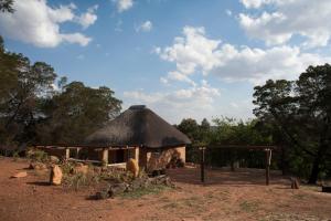 een hut met een rieten dak in een veld bij Stone Cottage in Tierpoort