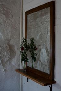 een spiegel met twee vazen bloemen op een plank bij Stone Cottage in Tierpoort