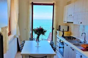 eine Küche mit einem Tisch mit einer Vase mit Blumen darauf in der Unterkunft Appartamento panoramico per 4 sul lungomare di Castellabate in Santa Maria di Castellabate + 6 Fotos