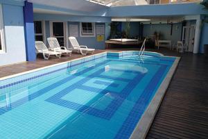 a large blue swimming pool with chairs and a table at Hotel Villa Michelon in Bento Gonçalves