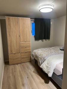 a bedroom with a bed and a wooden cabinet at Bright and pleasant basement apartment near downtown, Lys og trivelig kjellerleilighet i sentrumsnært in Kirkenes