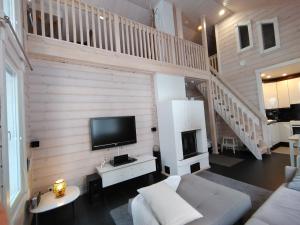 a living room with a couch and a tv on a wall at Aihki Pine Cottage, Iso-Syöte in Syöte