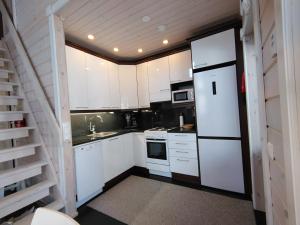 a kitchen with white cabinets and a white refrigerator at Aihki Pine Cottage, Iso-Syöte in Syöte