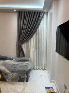 a bedroom with a bed and a window with curtains at Apartament Villal Banha in Kafr al Jazzār