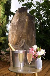 a table with two glasses of champagne and a vase of flowers at La Villa Du Menhir Chambre d'hôtes in Bize-Minervois