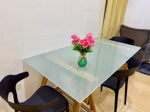 einen Glastisch mit einer Vase rosa Blumen drauf in der Unterkunft Kawaii StudioStay Kuala Terengganu in Kuala Terengganu