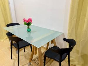 ein Tisch mit einer Vase mit rosa Blumen darin in der Unterkunft Kawaii StudioStay Kuala Terengganu in Kuala Terengganu