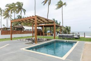 a swimming pool with a pavilion next to the ocean at Tills Beach Resort in Fetta