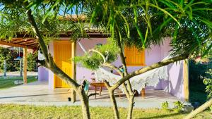 una casa con puerta amarilla, mesa y sillas en Hospedaria Hibisco Xandó - Caraíva, en Caraíva