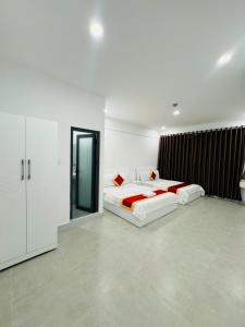 - une chambre blanche avec 2 lits et un miroir dans l'établissement Phú Gia 2307 Huỳnh Tấn Phát, à Hô-Chi-Minh-Ville