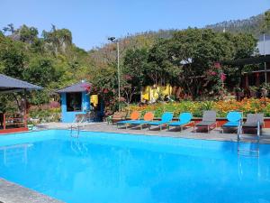 a swimming pool with blue and orange chairs and flowers at Catba Papillon Garden Bungalows & Resort in Cat Ba
