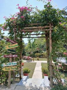 a wooden pergola with signs and flowers on it at Catba Papillon Garden Bungalows & Resort in Cat Ba