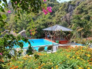 a swimming pool with chairs and flowers in front of a mountain at Catba Papillon Garden Bungalows & Resort in Cat Ba