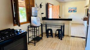 a kitchen with a counter with stools and a counter top at Hospedaria Hibisco Xandó - Caraíva in Caraíva