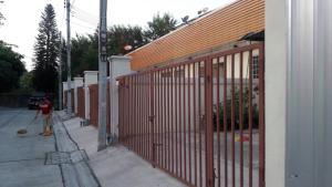 una persona con una escoba parada junto a una valla en บ้านเช่าดีๆเงียบสงบที่ลงตัว, en Ban Lat Tanot