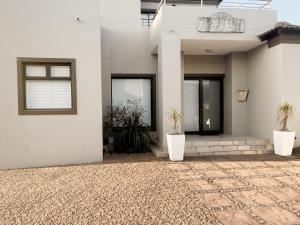 a white house with two potted plants in front of it at CasaCalme Guest House in Cape Town
