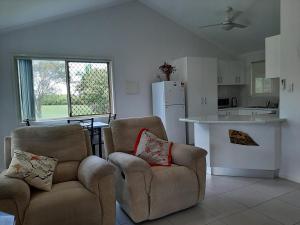 a living room with two chairs and a kitchen at Sanctuary Hills Cottage in Takura