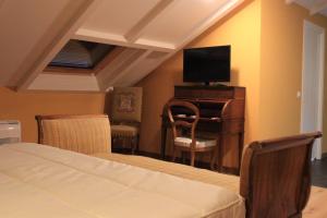 a bedroom with a bed and a desk with a television at Hostal Siglo XIX in Cacabelos