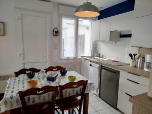 a kitchen with a table with chairs and a table cloth at gite notre désir 100 m de la mer in Jullouville-les-Pins +19 photos