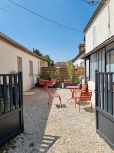 a patio with red chairs and tables and a fence at La Petite Cuvée confort & elegance in Beaune