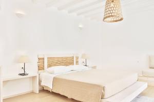 a white bedroom with a bed and a chandelier at Baba Houlakia in Houlakia