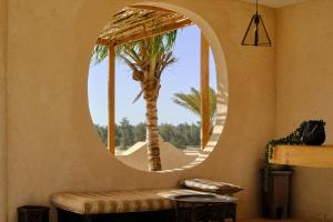 a circular mirror in a room with a palm tree at OKAÏ Oasis Desert Senegal in Lompoul