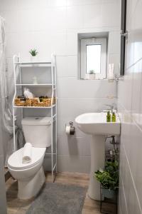 a white bathroom with a toilet and a sink at Stoa House in Mourné