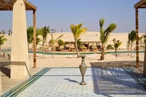a vase in the middle of a courtyard with palm trees at OKAÏ Oasis Desert Senegal in Lompoul