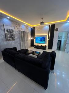 a living room with a black couch and a flat screen tv at Le spacieux bis in Dakar