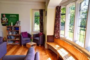 a living room with a couch and chairs and windows at YHA Beer in Seaton