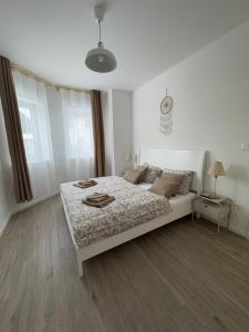 a white bedroom with a bed and a window at Caismarc apartment in centre of city Kežmarok in Kežmarok