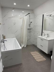a white bathroom with a tub and a sink at Caismarc apartment in centre of city Kežmarok in Kežmarok