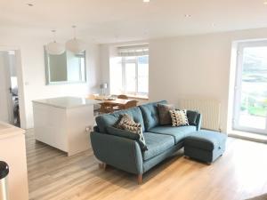 ein Wohnzimmer mit einer blauen Couch und einer Küche in der Unterkunft Beautiful 2 bed apartment with stunning sea views in Woolacombe