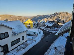 a small town with snow on the roofs of houses at Gehlberger Landhaus am Schneekopf / Ferienwohnung in Suhl
