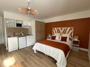 a bedroom with a large bed and a kitchen at Appart-Hôtel Rouillac in Rouillac