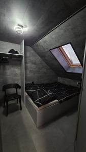 a small bedroom with a bed and a chair at Secret Barn in Michalczowa