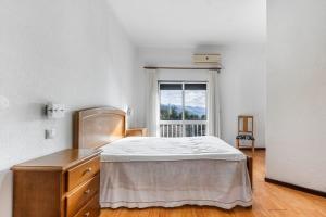 a white bedroom with a bed and a window at O Pimpao in Geres
