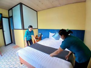 two people making a bed in a hotel room at Catba Papillon Garden Bungalows & Resort in Cat Ba