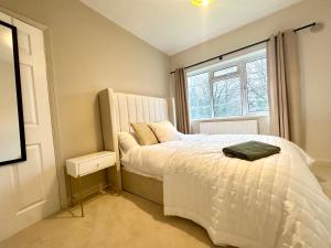 a bedroom with a white bed and a window at Lovely spacious 3 double bed flat, LS17 in Leeds