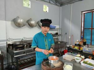 a man standing in a kitchen preparing food at Catba Papillon Garden Bungalows & Resort in Cat Ba