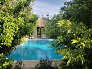 a swimming pool in the middle of a resort with trees at Belle villa in Poponguine