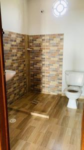 a bathroom with a toilet and a brick wall at Cabaña Umpalita para 4 cuatro personas in Los Santos