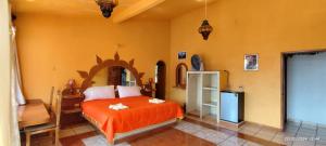 a bedroom with a bed with an orange bedspread at Castillo del Rey in Valle de Bravo