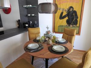a dining room table with chairs and a monkey poster at Wien Schwechat Apartment Airport in Schwechat