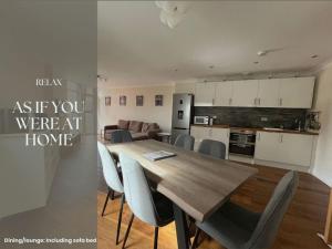カーディフにあるUltra-Luxury City centre 2 bed apartment, with FREE parkingの木製のテーブルと椅子のあるキッチンとリビングルーム
