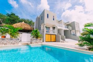 a villa with a swimming pool in front of a house at Casa Sun's Buddy in Willemstad